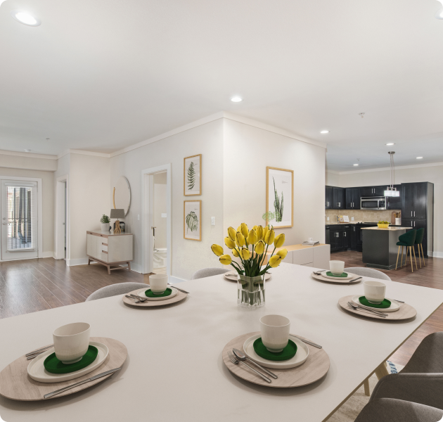 A modern apartment featuring a dining table and chairs adjacent to an open kitchen equipped with recessed ceiling lighting at MAA Times Square luxury apartments in McKinney, TX