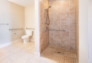 A spacious bathroom with a modern-style light brown tiled stand-up shower at MAA Times Square luxury apartments in McKinney, TX