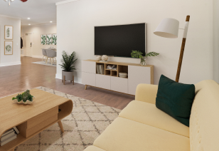 An upscale living room with a creamy brown couch, a wall-mounted TV, and a sleek wood coffee table, all complemented by hardwood flooring at MAA Times Square luxury apartments in McKinney, TX