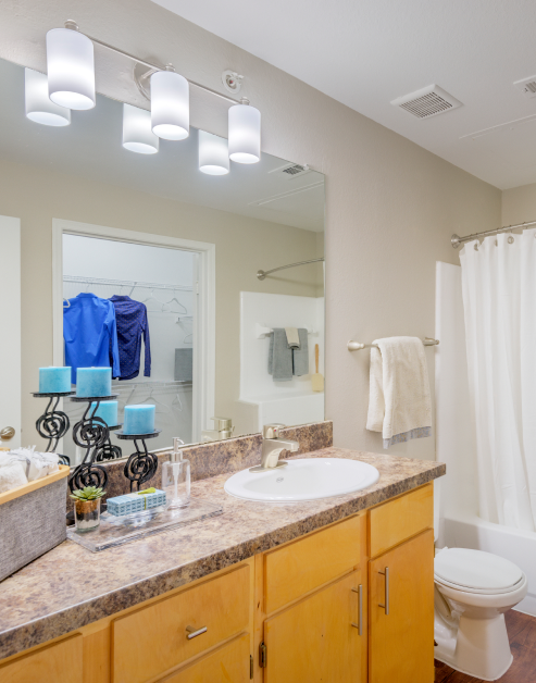 Modern-style bathroom with a single vanity sink on granite countertop and large vanity mirror at MAA Uptown Village luxury apartments in Dallas, TX