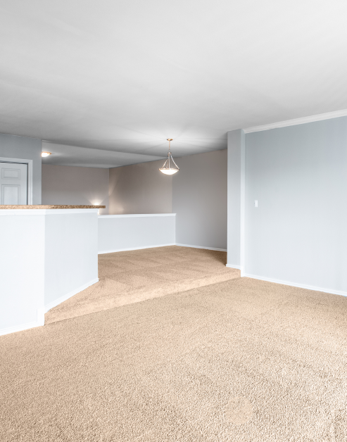 Empty carpeted loft master bedroom with ceiling pendant light fixture at MAA Valley Ranch luxury apartments in Irving, TX