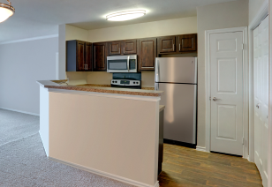 Open kitchen with dark brown cabinets and stainless steel fridge at MAA Valley Ranch luxury apartments in Irving, TX