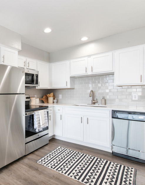 Upscale modern kitchen with upgraded stainless steel appliances, white wood cabinets and sleek wood floors at MAA Worthington luxury apartments in Dallas, TX
