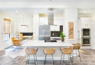 Modern kitchen with a large center island, wicker bar stools, stainless steel appliance and white cabinets with wood flooring at MAA Worthington luxury apartments in Dallas, TX