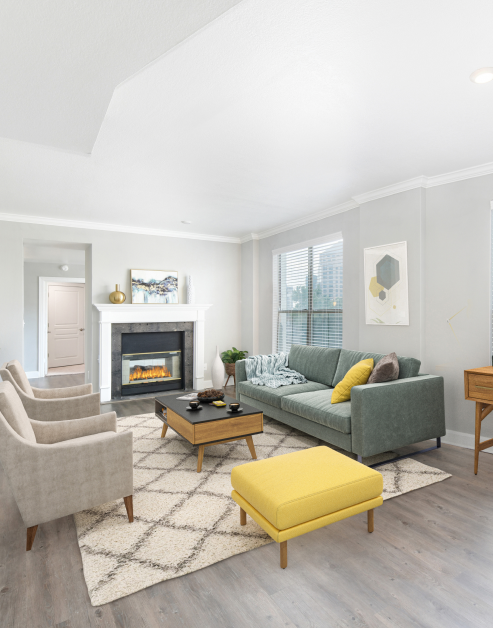 A living room featuring a fireplace next to a modern couch set with a sleek coffee table, large windows and hardwood floors at MAA Worthington luxury apartments in Dallas, TX