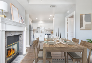 A modern living room features a fireplace, wooden dining table and bright lighting next to a kitchen at MAA Worthington luxury apartments in Dallas, TX
