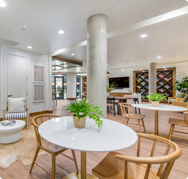 Community center with multiple tables and chairs with marble columns and recessed lighting on wood floors at MAA 510 luxury apartments in Houston, TX