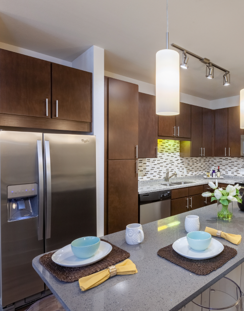Modern-style kitchen with dark wood cabinets, stainless steel appliances with patterned tile backsplash and grey countertops at MAA 510 luxury apartments in Houston, TX