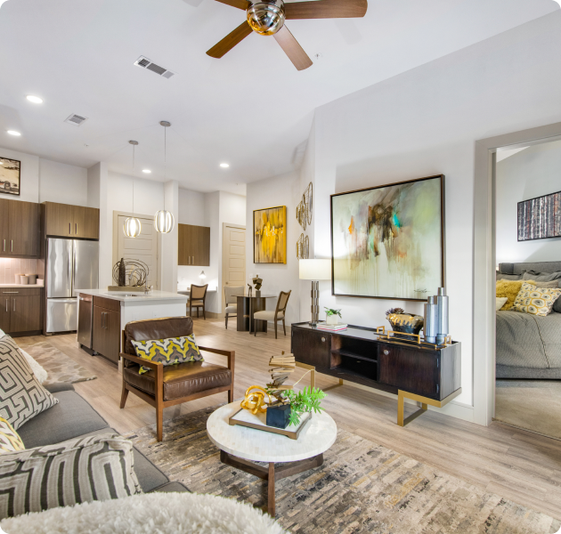 Apartment living room area with an armchair, marble top coffee table and wooden cabinet near kitchen and dining area at MAA Afton Oaks luxury apartments in Houston, TX