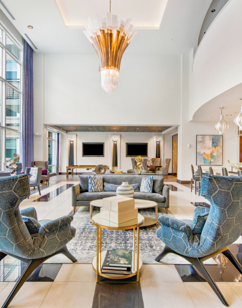 Community clubhouse with large stylish chandelier and cozy sitting area with marble coffee tables and wall length windows at MAA Afton Oaks luxury apartments in Houston, TX