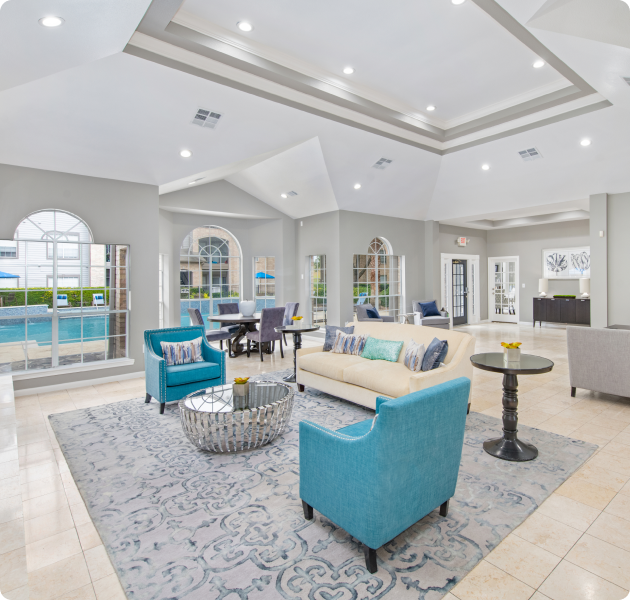 A modern community clubhouse with vaulted ceiling and French doors with multiple sitting areas at MAA Energy Park luxury apartments in Houston, TX