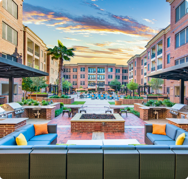 Modern community with outdoor kitchen and grilling areas with a sparkling swimming pool surrounded by lush greenery at MAA Greater Heights luxury apartments in Houston, TX