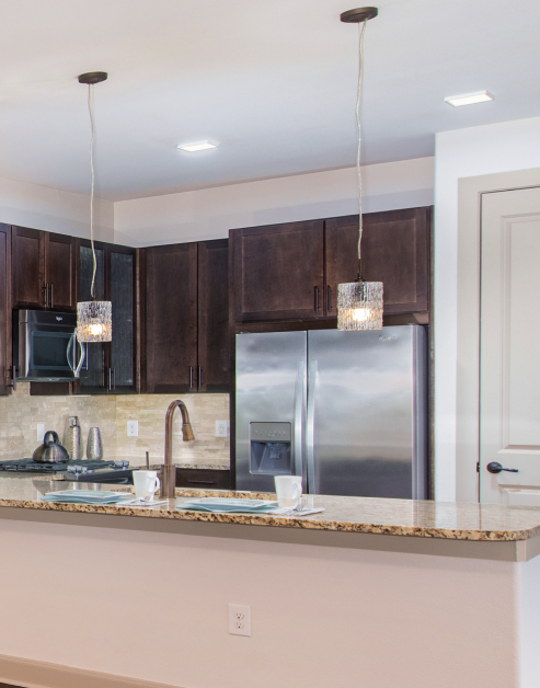 Modern-style kitchen with wooden cabinets, granite countertops and stainless steel appliances at MAA Greater Heights luxury apartments in Houston, TX