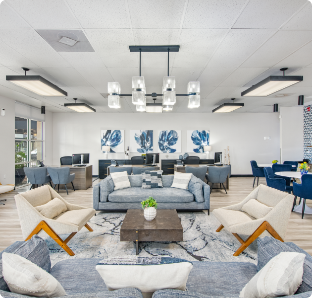 Modern-style community leasing office with multiple seating areas and stylish hanging light fixtures and multiple customer service desk stations with computers at MAA Midtown Square luxury apartments in Houston, TX