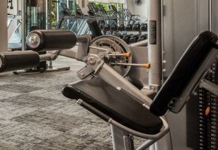 Close up view of fitness center leg extension machine surrounded by various gym equipment at MAA Park Point luxury apartments in Houston, TX