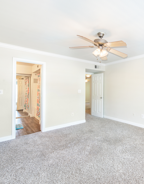 Carpeted master bedroom with ceiling fan and an en suite bathroom at MAA Ranchstone luxury apartments in Houston, TX