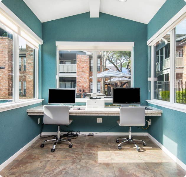 Community clubhouse with vaulted ceiling and tile floors with an internet café and large picture windows in natural light at MAA Valleywood luxury apartments in the Woodlands, TX