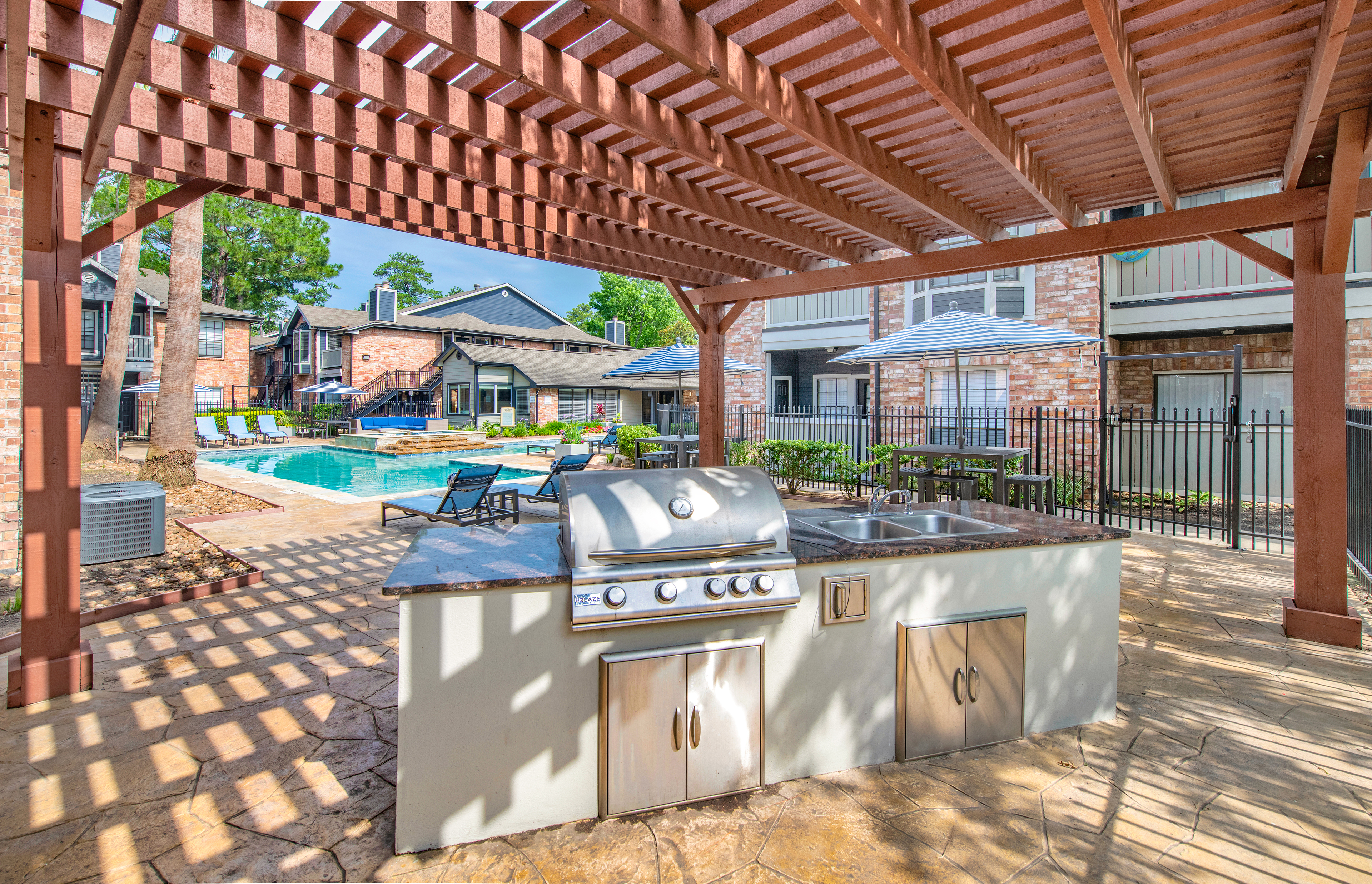 Poolside covered wooden pergola with outdoor grilling station at MAA Valleywood luxury apartments in the Woodlands, TX