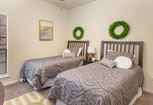 Carpeted bedroom with wall art and twin beds at MAA Valleywood luxury apartments in the Woodlands, TX