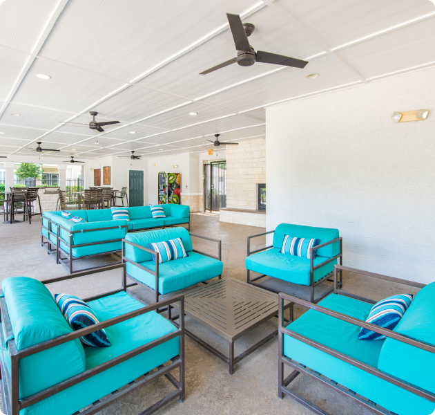 Community clubhouse with a high ceiling and ceiling fans, with multiple aqua blue cushioned seating areas at MAA Haven at Blanco luxury apartments in the San Antonio, TX