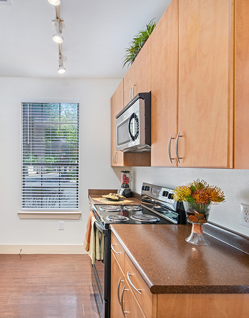 Kitchen with track lighting, light brown cabinets and upgraded appliances on wood floors at MAA Westover Hills luxury apartments in San Antonio, TX