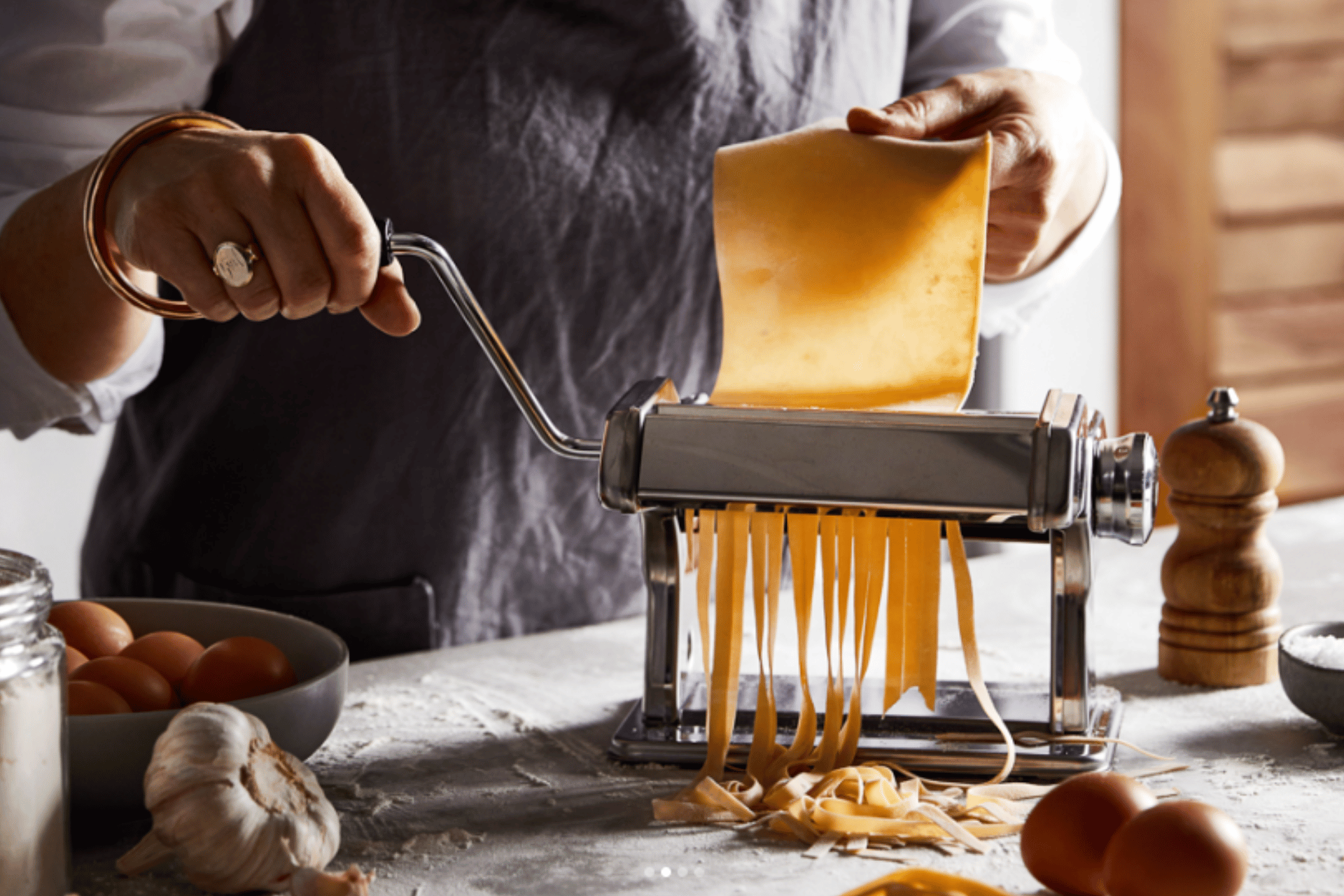 Feeding pasta through a pasta machine to make fettucine