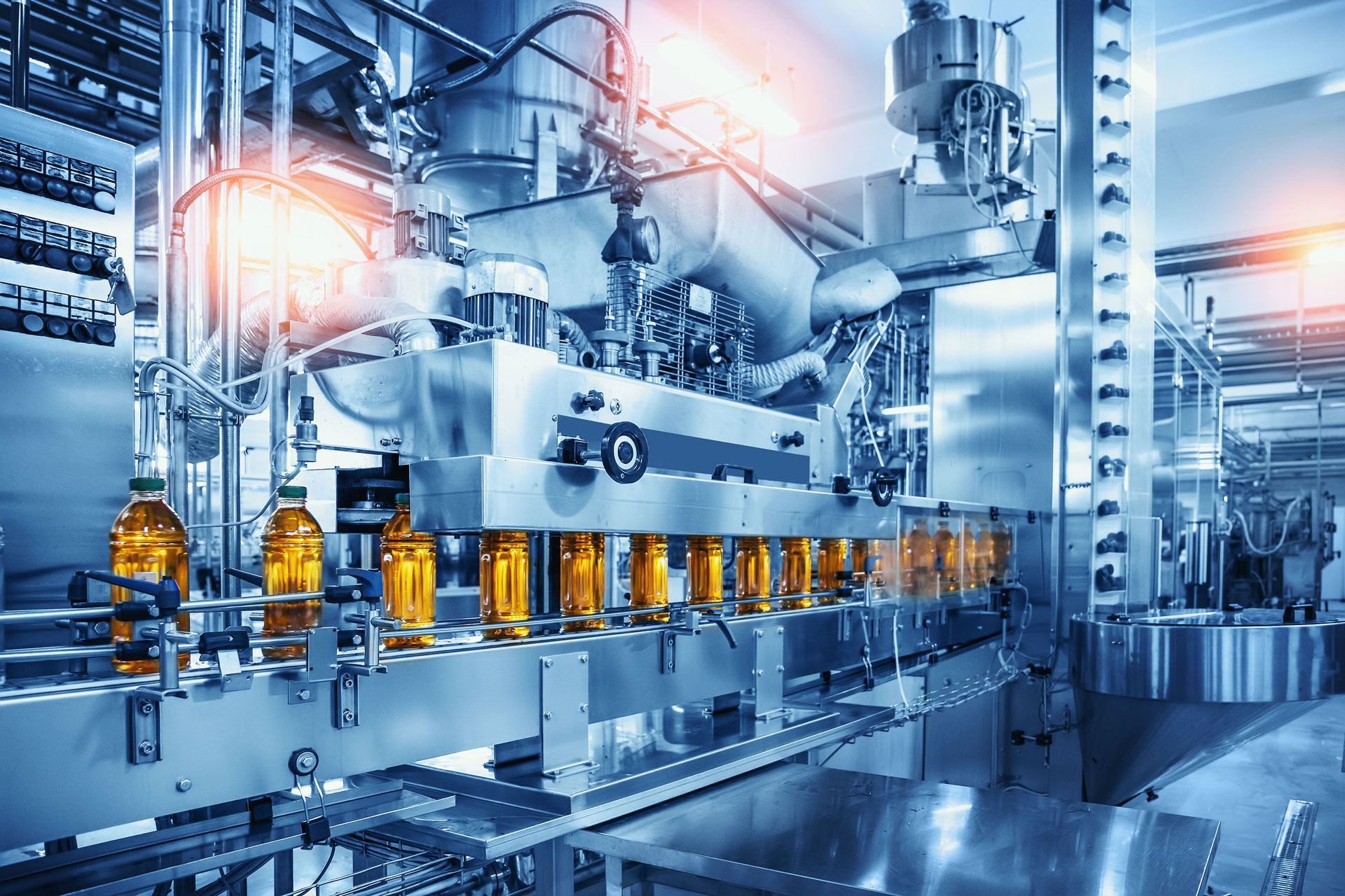 Conveyor belt with juice bottles on beverage factory interior in blue color.