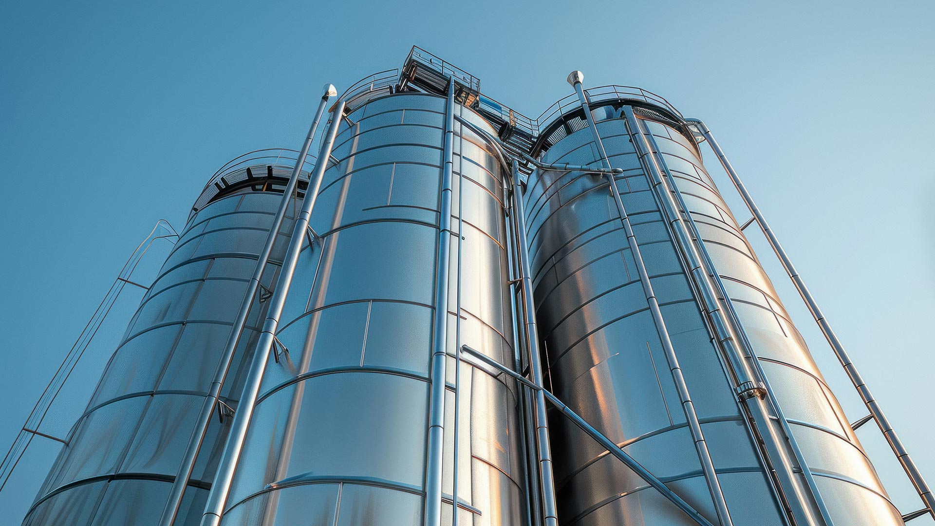 Industrial stainless steel silos against a clear sky background