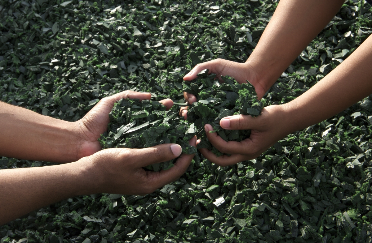 Hands holding small pieces of rubber ready for recycling