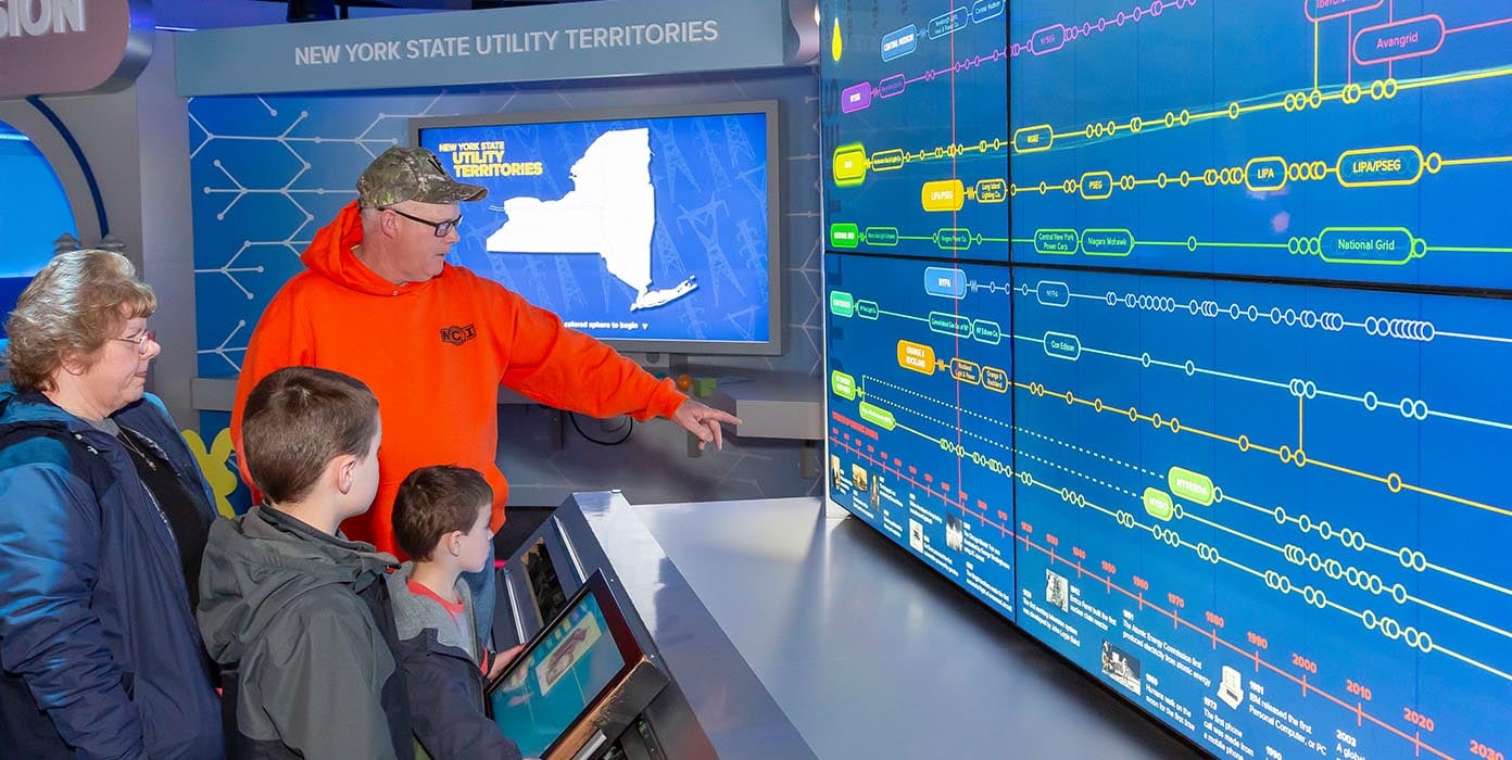 A guy explaining two kids along with a lady about NYPA Energy 