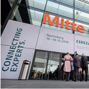 Eingang einer Messe mit Außenwerbung in welche Besucher hineingehen