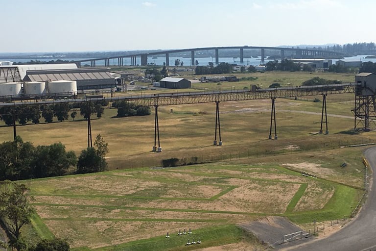 Remediated industrial site with grassy land and elevated conveyor structures.