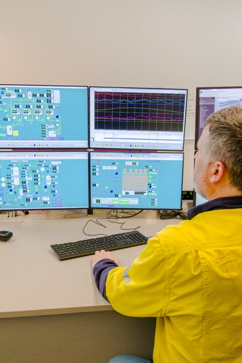 operator monitoring industrial control systems on multiple computer screens