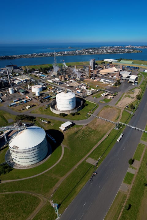 Aerial view of a large industrial facility with storage tanks, processing buildings, and waterways