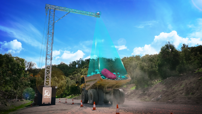 A dump truck parked under a gantry with a digital overlay showing the FRAGTrack™ Gantry scanning the rock fragments.