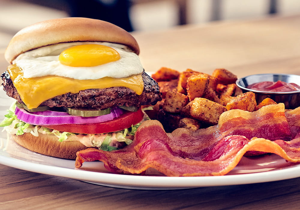 BFG EGG BURGER Our signature half-pound BFG burger, toasted bun, fully dressed with sharp Cheddar and special sauce, topped with a fried egg, served with seasoned breakfast potatoes and applewood smoked bacon.