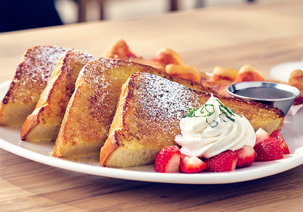 CRÈME BRÛLÉE FRENCH TOAST Grand Marnier and orange zest soaked brioche bread, served with chef-crafted whipped cream, mint, fresh strawberries, served with applewood smoked bacon.
