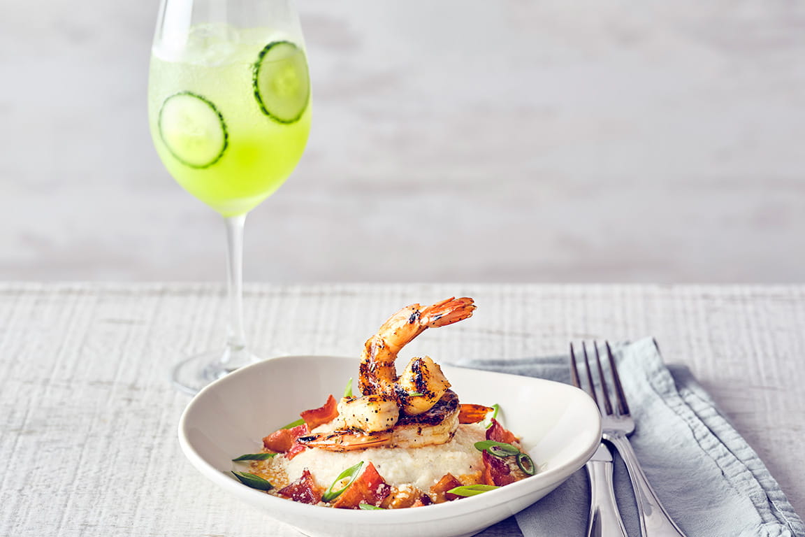 COURSE 1 SHRIMP & GRITS Wood-grilled shrimp topped with a creamy Creole sauce, served over mozzarella cheese-infused grits, finished with green onions, parmesan cheese and bacon.  CUCUMBER MELON SPRITZ Our house-infused cucumber vodka, Midori melon liqueur, and fresh sour, topped with Fever-Tree Lime & Yuzu sparkling water balances the rich, smoky Creole sauce creating clean, refreshing sips.