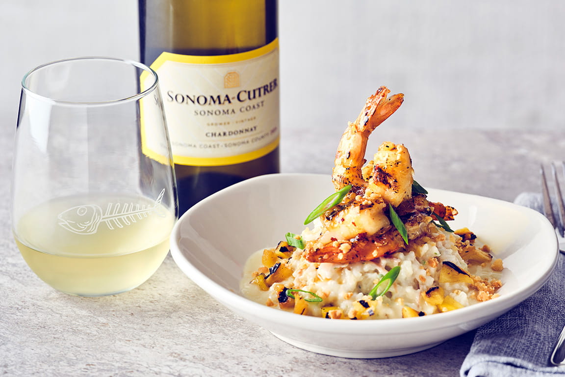 COURSE 2  PINEAPPLE GLAZED SHRIMP  Wood-grilled jumbo shrimp with sweet and spicy pineapple glaze, served over creamy coconut risotto, and finished with charred pineapple, lemon butter and toasted macadamia nuts.   SONOMA-CUTRER CHARDONNAY  This chardonnay's structure supports the richness of the coconut and butter, while its brightness elevates the shrimp and tropical glaze.