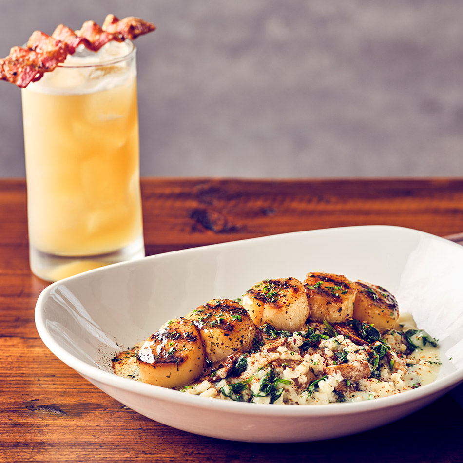 COURSE 3  SEA SCALLOPS SPINACH RISOTTO Wood-grilled sea scallops served over creamy spinach and mushroom risotto, drizzled with lemon butter, and garnished with our signature chipotle seasoning.  MAPLE BOURBON SOUR WhistlePig PiggyBack bourbon, rich WhistlePig barrel-aged maple syrup and fresh citrus, topped with peppered bacon. The cocktail’s warm toasted sugar and smoky notes complement the scallops’ natural sweetness and wood-grilled char.