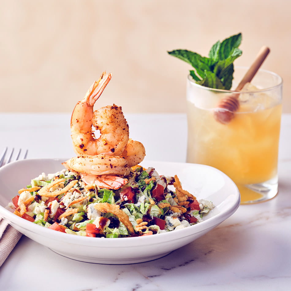 COURSE 2  COASTAL CHOPPED SALAD Iceberg lettuce tossed with applewood bacon and crispy onions in chef-crafted drunken ranch, finished with diced tomatoes, blue cheese, balsamic reduction, and chilled Old Bay® citrus shrimp.  GOLD RUSH This modern favorite blends the smooth, full-bodied character of Woodford Reserve bourbon with fresh sour mix and house-made honey syrup, adding warmth and richness against the salad’s cool crunch.