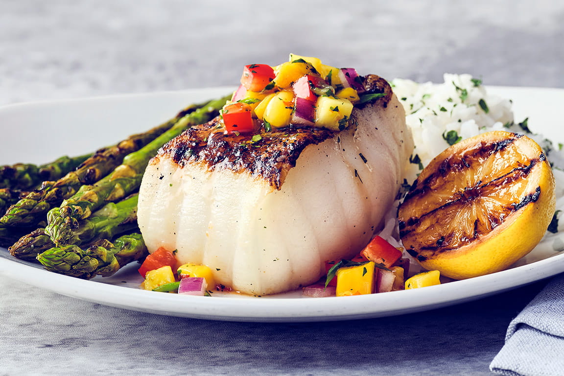 MANGO SALSA CHILEAN SEA BASS Wood-grilled, topped with mango salsa, served with jasmine rice and grilled asparagus.