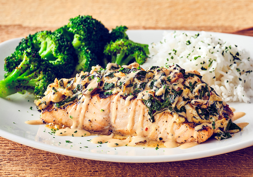 DYNAMITE SALMON Wood-grilled Atlantic salmon, with a creamy spinach, mushroom, and lump crab dynamite topping, served with two signature sides.