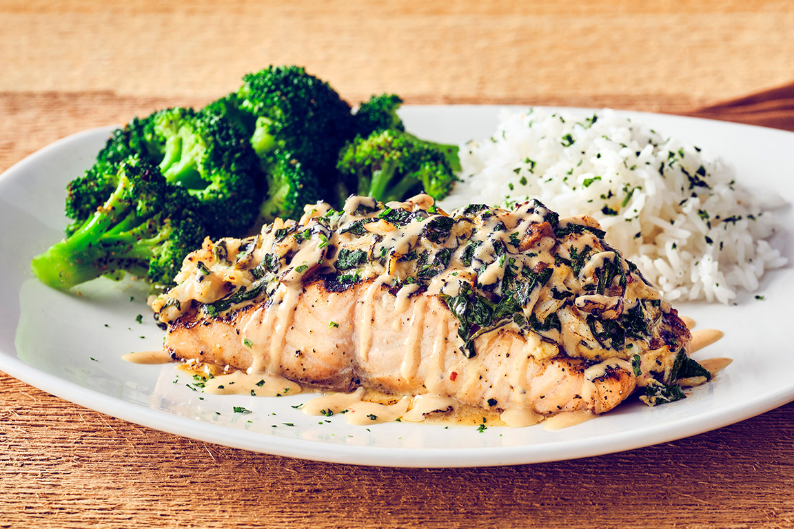 DYNAMITE SALMON Wood-grilled Atlantic salmon, with a creamy spinach, mushroom, and lump crab dynamite topping, served with two signature sides.