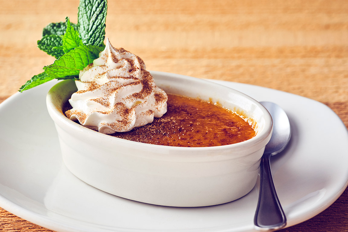 PUMPKIN CRÈME BRÛLÉE  Creamy house-made pumpkin custard topped with a crisp caramelized sugar crust, with fresh whipped cream and a mint garnish.