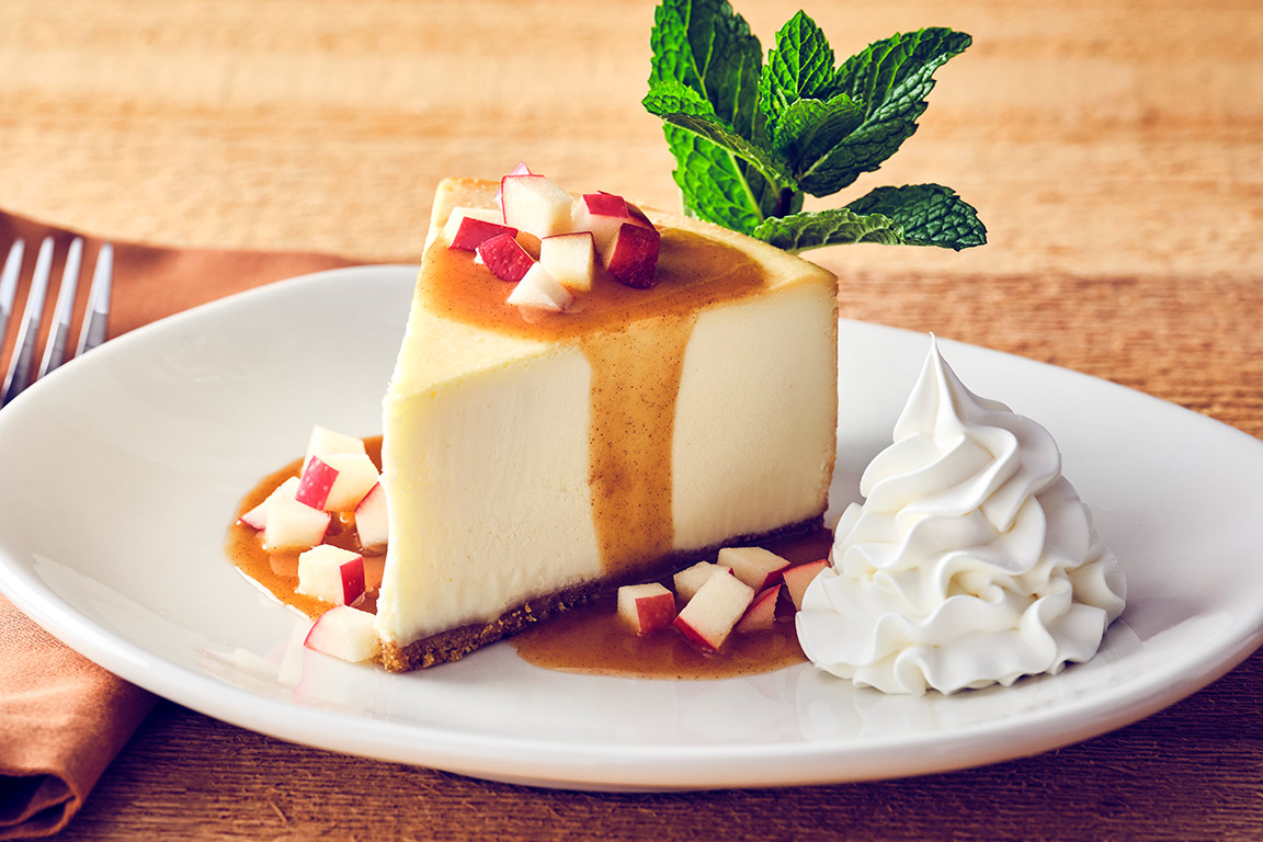 SPICED APPLE CHEESECAKE Warm spiced apple cider sauce, diced apples, with fresh whipped cream and a mint garnish.