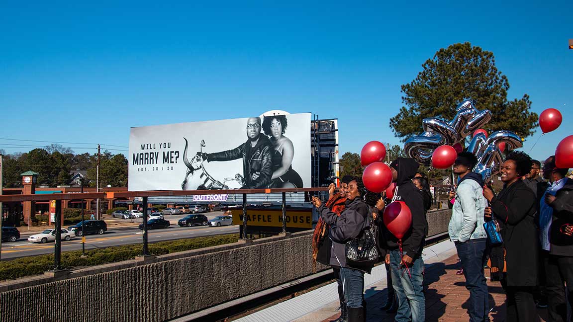 Crowd gathered around wedding proposal billboard