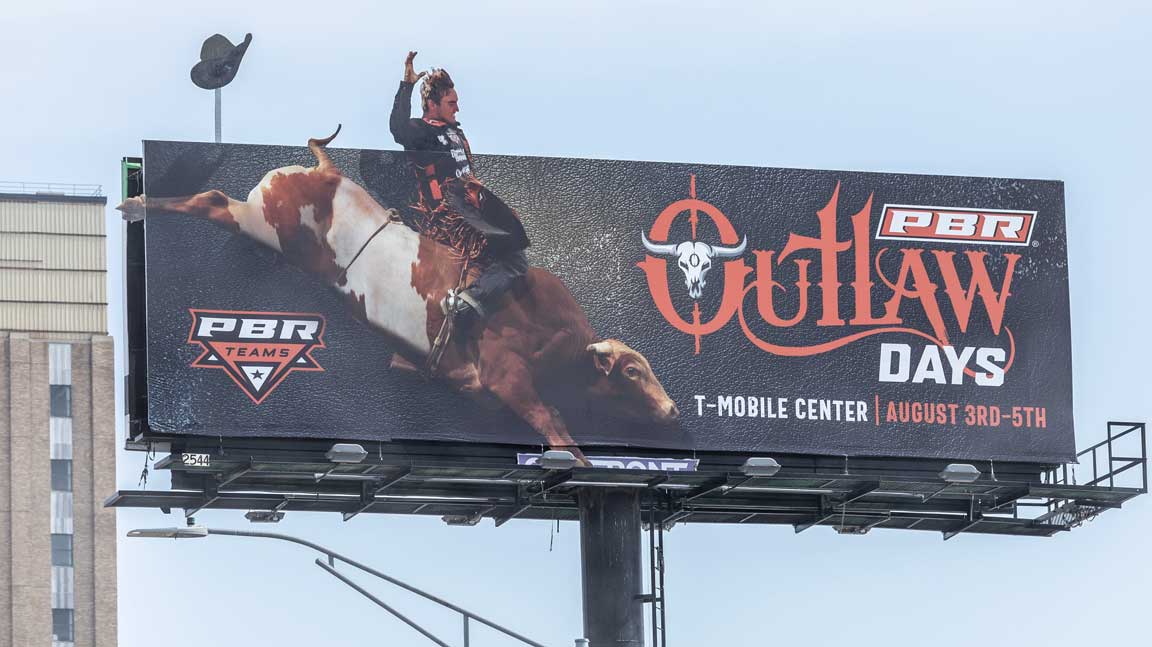 PBR Teams Outlaw Days billboard in Kansas City depicting cowboy with hat flying off