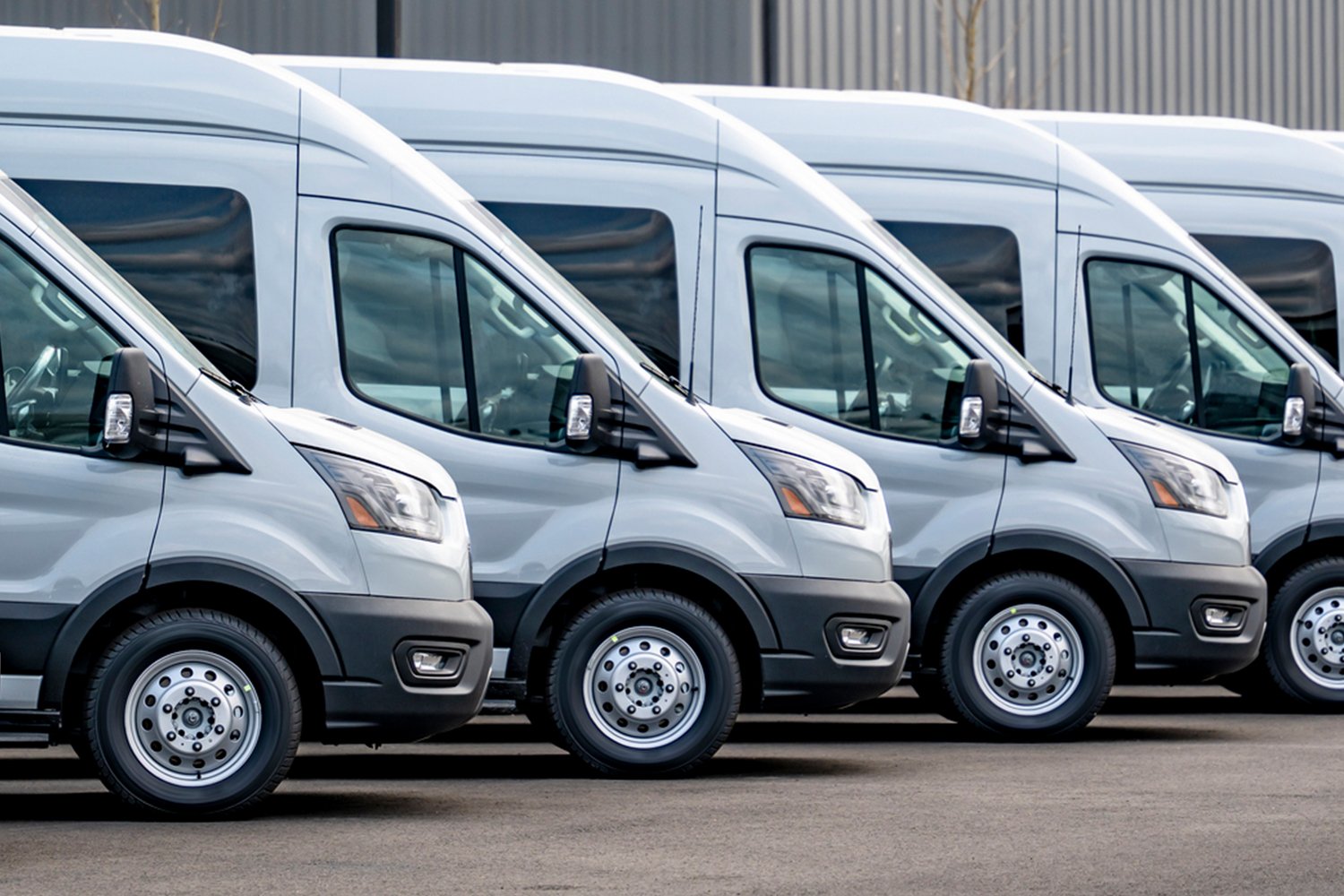 A row of white vans in a parking lot