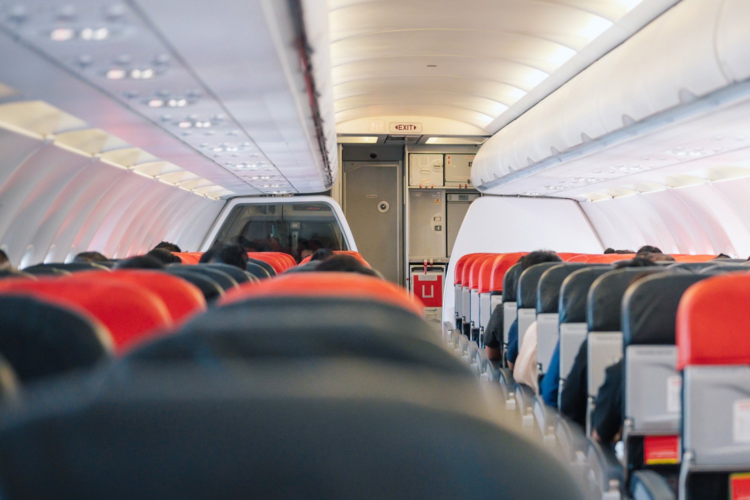 An airplane interior showcasing sleek black and red seats, illustrating modern aviation design.